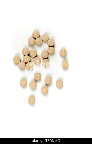 Comprimés de couleur tan éparpillées sur un fond blanc Banque D'Images