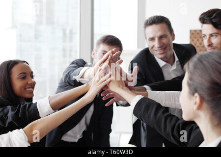 Happy business team en haut cinq avec leurs mains dans le bureau Banque D'Images