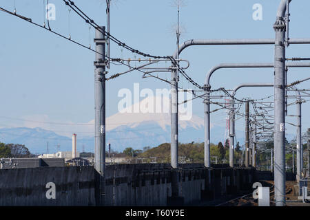 Le Mont Fuji apparaît dans la distance entre les lignes électriques et les structures construites le long des voies sur la ligne Tsukuba Express Station de Moriya, Ibaraki. Banque D'Images