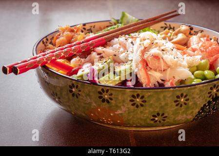 Bol Poke faite avec des fruits de mer, légumes, fruits et noix. Banque D'Images