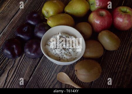 Yaourt naturel avec son ensemble les prunes, les poires, les pommes et les kiwis sur fond de bois rustique Banque D'Images
