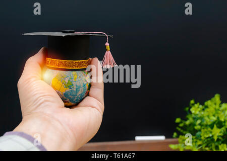 La réussite éducative en concept. L'éducation sera d'accroître les connaissances, et il aura une valeur pour la vie. Le globe est placé sur la main et porté avec un diplômés Banque D'Images