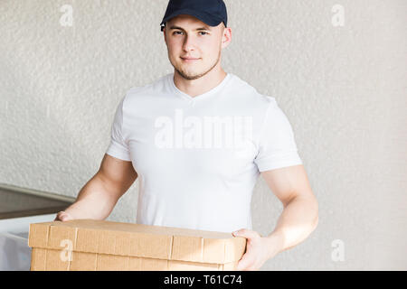 La livraison fort, musclé homme Chargement des boîtes en carton pour déménagement d'un appartement. travailleur professionnel du transport, de l'homme en salopette chargeurs Banque D'Images