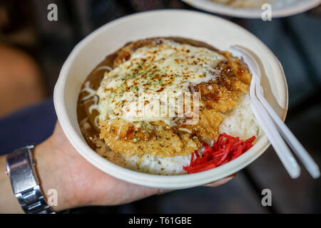 Tonkatsu ; la cuisine japonaise traditionnelle, croustillant de porc frit avec des sauces sur le dessus et le riz sous elle, dans le plat de papier. Rue des aliments de Bangkok, Thaïlande. Banque D'Images