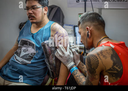 Un homme faire un tatouage à un stand lors de la convention de tatouage annuel dans la capitale Banque D'Images