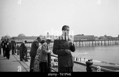 Un homme bénéficiant d'une glace sur la promenade. Photographie amateur à partir d'une collection de la famille en vacances au bord de la mer en Angleterre. c1950 Photo de Tony Henshaw Banque D'Images