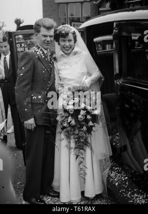 Photographie amateur à partir d'une collection de la famille. À la suite d'un mariage à l'église les mariés posent par leur voiture de mariage en Angleterre.c1950 Photo de Tony Henshaw Banque D'Images