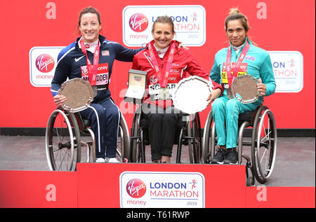 La suisse Manuela Schar (centre) célèbre avec le trophée après avoir remporté le Marathon en fauteuil roulant de la femme aux côtés de la deuxième places USA's Tatyana McFadden (à gauche) et troisième placé l'Australie's Madison de Rozario (à droite) au cours de la Virgin Money 2019 Marathon de Londres. Banque D'Images