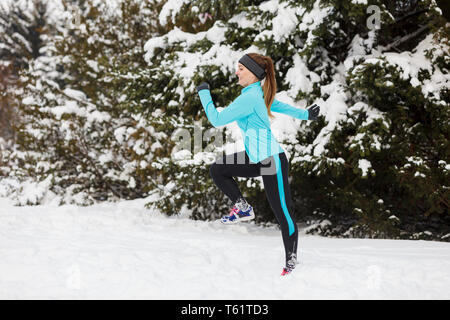 Les gens de l'hiver sport concept. Jeune femme faisant de l'exercice dans parc. Belle fille du jogging autour de l'extérieur, profiter de l'heure d'hiver. Femme portant haut bleu et Banque D'Images