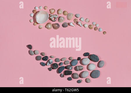 Signe de yin yang énoncés du noir et blanc des pierres et coquillages isolé sur fond rose.feng shui. la force. contraire forces.l'homme et la femme c Banque D'Images