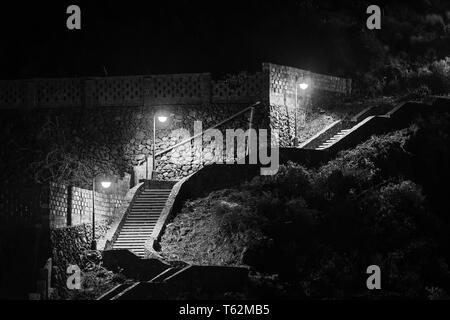 Un escalier éclairé à Los Cancajos, La Palma, Espagne. Noir et blanc voir la nuit, l'escalier mène de la plage sur une route. Banque D'Images