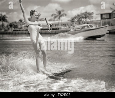 1950 EXCITED WOMAN SKI NAUTIQUE BATEAU DE POUVOIR ACCÉLÉRER EN ARRIÈRE-PLAN SUR CANAL bordée de palmiers MIAMI BEACH FLORIDE USA - un478 HAR001 HARS FEMELLES VIE SANTÉ États-unis MESDAMES PLEINE LONGUEUR FORME PHYSIQUE PERSONNES UNITED STATES OF AMERICA EXPRESSIONS SPORTIVES B&W FORCE PHYSIQUE ACTIVITÉ AVENTURE JOYEUSE EXCITATION EN LOISIRS SUR L'EAU BATEAU PUISSANCE ACCÉLÉRATION SOURIRES CONCEPTUEL SKI SOUPLESSE MUSCLES JOYEUSE PALMIER ÉLÉGANT MAILLOT DE MIAMI BEACH FL CANAL NOIR ET BLANC DE L'ORIGINE ETHNIQUE CAUCASIENNE HAR001 une pièce à l'ANCIENNE Banque D'Images