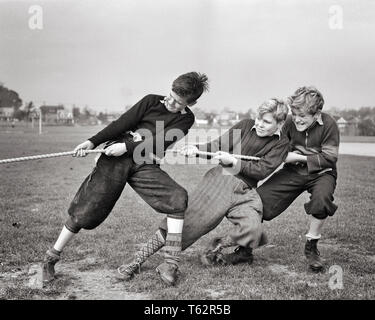 Années 1930 Années 1940 Trois ADOLESCENTS PORTANT DES PANTALONS PULLS TRICOTÉS GENOU CHAUSSETTES SNEAKERS TIRANT ENSEMBLE SUR LA CORDE DANS L'aire de jeux de tir à la corde - b11079 HAR001 Paire de HARS tirant l'EXPRESSION BANLIEUE VIEUX CORPS TEMPS NOSTALGIE FRÈRE ANCIENNE MODE DE REMISE EN FORME DU VISAGE JUVÉNILE 1 équilibre sain d'ÉQUIPE DE SÉCURITÉ DE L'ATHLÈTE DE LA CONCURRENCE HEUREUX JOIE FRÈRES VIE SANTÉ RURAL COPIE ESPACE DE REMISE EN FORME PHYSIQUE PERSONNES INSPIRATION HOMMES ADOLESCENT ATHLETIC CHAUSSURES DE FRÈRES ET SŒURS DES EXPRESSIONS DE CONFIANCE B&W L'ACTIVITÉ TRICOT AVENTURE JOYEUSE PHYSIQUE ET FORCE PUISSANTE EXCITATION CONCOURS FIERTÉ DE LOISIRS SUR Banque D'Images