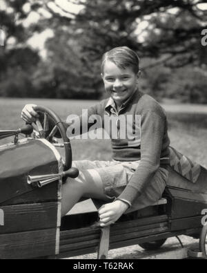 1930 SMILING PRETEEN BOY LOOKING AT CAMERA ASSIS DERRIÈRE LE VOLANT D'ACCUEIL CONSTRUIT TACOTS VOITURES DE COURSE EN BOIS - b14550 HAR001 CONCOURS DE SÉCURITÉ DES VÉHICULES BLONDE HARS HEUREUX JOIE SATISFACTION VITESSE MODE DE VIE ACCUEIL CÉLÉBRATIONS COPIE ESPACE INSPIRATION PLEINE LONGUEUR DE TRANSPORT AUTOMOBILE RISQUE D'EXPRESSIONS MÂLES B&W EYE CONTACT LIBERTÉ SUCCÈS RÊVES BONHEUR aventure joyeuse excitation DERBY VICTOIRE FORCE AUTOS OCCASION DE FIERTÉ L'INNOVATION LOISIRS PRÉADOLESCENT SOURIRES JOYEUX VÉHICULES AUTOMOBILES CONCEPTUEL ÉLÉGANT SOAPBOX CRÉATIVITÉ MINEURS PRÉ-ADO PRÉ-ADO GARÇON DÉTENTE Banque D'Images