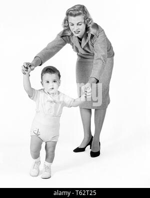 Années 1950 Années 1960 CONCERNÉ Fière mère regardant aider bébé garçon PREMIERS PAS DE MARCHE - b8380 HBB001 HARS SANTÉ ACCUEIL ESPACE COPIE DE LA VIE DES FEMMES LES PERSONNES QUI S'OCCUPENT LES HOMMES B&W OBJECTIFS CONTACT VISUEL élégant de la maternité Bébé garçon mi-croissance des juvéniles DES PROFILS MID-ADULT WOMAN MAMANS PARENTHOOD VIVRE ENSEMBLE NOIR ET BLANC à l'ANCIENNE Origine ethnique Caucasienne Banque D'Images