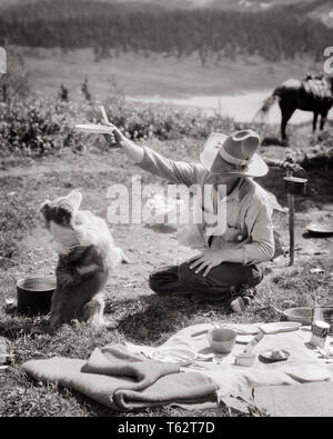 Années 1920 Années 1930 HOMME DUDE RANCH GUIDE DES SENTIERS COWBOY DANS CAMPING CAMP MENDICITÉ TENTANT CHIEN À S'ASSEOIR AVEC PLATEAU DE NOURRITURE - c3299 HAR001 EMPLOI VIE HARS MENDICITÉ RURALE ESPACE copie des personnes qui s'occupent de l'Ouest mâles CAMPING B&W TENTATION DE COMPÉTENCES COMPÉTENCES PROFESSION SUCCÈS AVENTURE MAMMIFÈRES DANS DES LOISIRS DE CANINES À L'AUTORITÉ PROFESSIONS POOCH CONCEPTUEL SOUPER DUDE RANCH GUIDE DU SENTIER ÉLÉGANT MAMMIFÈRE CANIN ADULTES MI-homme mi-RELAXATION ADULTES ENSEMBLE NOIR ET BLANC DE L'ORIGINE ETHNIQUE CAUCASIENNE HAR001 old fashioned tentant Banque D'Images