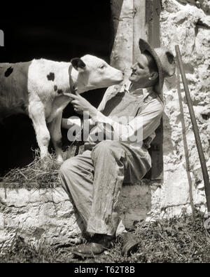 Années 1920 L'HOMME PRODUCTEUR DE LAIT EN SALOPETTE STRAW HAT SITTING IN BARN PORTE AVEC VEAU AYRSHIRE PRÈS DE WEST CHESTER EN PENNSYLVANIE USA - c3693 HAR001 STYLE GRANGE HARS EMPLOIS laitières rurales États-unis personnes vache pleine longueur BRETELLES UNITED STATES OF AMERICA L'AGRICULTURE SOINS HOMMES PROFESSION EXPRESSIONS VEAUX Bovins B&W L'OCCUPATION COMPÉTENCES COMPÉTENCES CARRIÈRES JOYEUX BONHEUR PA AGRICULTEURS FIERS DE VACHES PRÈS DE PROFESSIONS SOURIRES JOYEUX CHAPEAU DE PAILLE CONCEPTUEL SALOPETTE ÉLÉGANT MAMMIFÈRE CROISSANCE MID-ADULT MAN MI-NOIR ET BLANC DE L'ORIGINE ETHNIQUE CAUCASIENNE HAR001 domestiqués à l'ancienne de l'élevage Banque D'Images