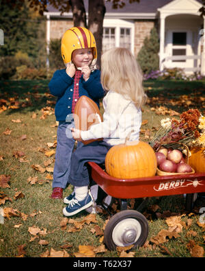 1960 YOUNG BOY WEARING FOOTBALL HELMET SMILING AT YOUNG BLONDE WOMAN SITTING ON AMERICAN FOOTBALL RED WAGON - KH1745 HAR001 HARS NOSTALGIE STYLE ANCIEN WAGON DE COUR JUVÉNILE COFFRE STYLE DE VIE JOIE MAISONS FEMELLES ACCUEIL NATURE VIE COPIE Espace demi-longueur d'AMITIÉ MÂLES RÉSIDENTIEL BÂTIMENTS POMMES BONHEUR LOISIRS EXTÉRIEURS PROTECTION AUTOMNE FEUILLAGE HOMES RESIDENCE RED WAGON de ballons de football américain ensemble la croissance des juvéniles de l'origine ethnique caucasienne d'AUTOMNE FEUILLAGE D'AUTOMNE HAR001 old fashioned Banque D'Images