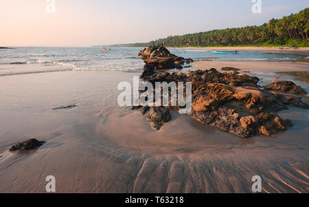 Chera rock en plein milieu de la plage de sable fin bordée de palmiers et de bateau en bois donnant sur la mer d'Oman au coucher du soleil près de Thottada village, New Delhi, Inde. Banque D'Images