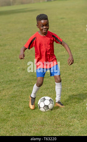 Hampshire, England, UK. Avril 2019. Un joueur de neuf ans dribble le ballon de soccer pendant une session de formation dans un parc public. Banque D'Images