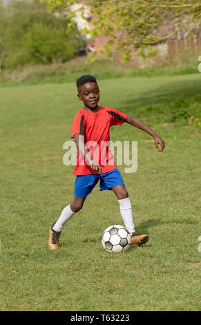 Hampshire, England, UK. Avril 2019. Un joueur de neuf ans dribble le ballon de soccer pendant une session de formation dans un parc public. Banque D'Images