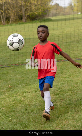 Hampshire, England, UK. Avril 2019. Un jeune joueur de football à la défense de l'objectif au cours d'une session de formation dans un parc public. Banque D'Images