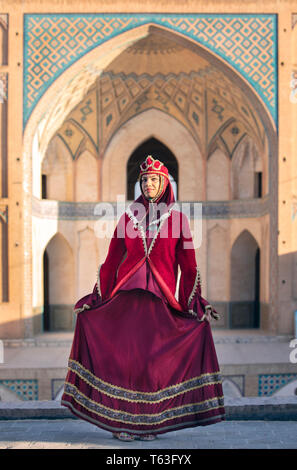 Belle jeune femme iranienne habillés en costume traditionnel rouge dans une mosquée à Kashan Banque D'Images