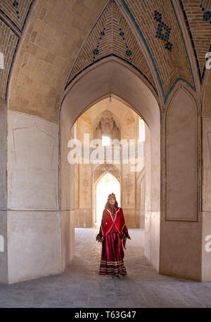 Belle jeune femme iranienne habillés en costume traditionnel rouge dans une mosquée à Kashan Banque D'Images