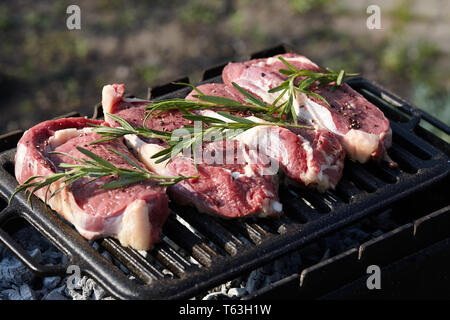 Les steaks juteux crus la cuisson sur le gril en plein air Banque D'Images