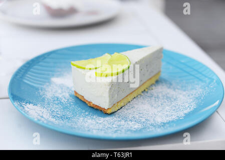 Belle de savoureux dessert cheesecake au mascarpone lumineux avec de la chaux sur une plaque bleue dans un restaurant sur la table, bonne nourriture Banque D'Images