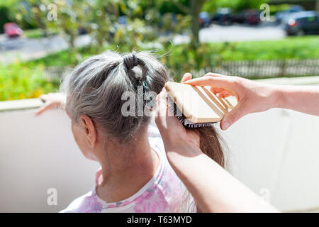 Jeune femme peigne les cheveux d'une vieille femme Banque D'Images