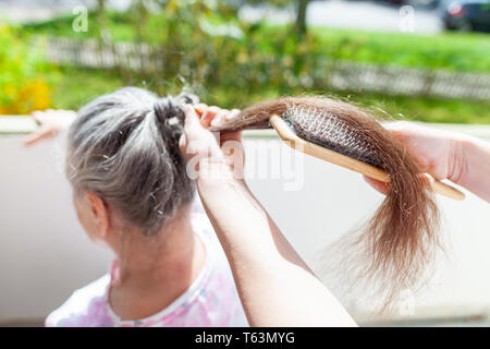 Jeune femme peigne les cheveux d'une vieille femme Banque D'Images