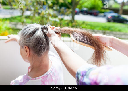 Jeune femme peigne les cheveux d'une vieille femme Banque D'Images