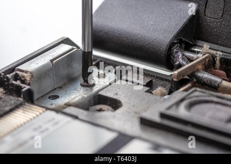 Le tournevis se dévisse le boulon de fixation de l'ancien conseil de l'ordinateur processeur poussiéreux. Nettoyage et réparation de l'électronique de démontage. Partie d'ordinateur portable Banque D'Images