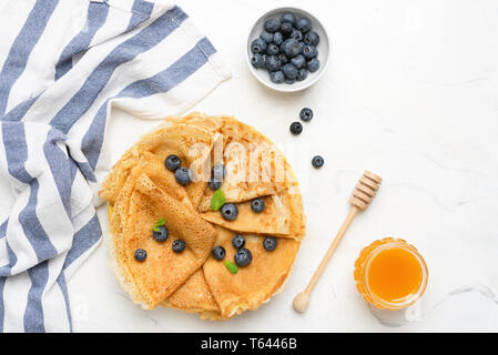 Crêpes ou blinis avec les baies fraîches et de miel sur fond blanc. Vue de dessus de table with copy space Banque D'Images