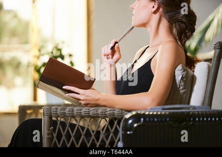 Pensive woman writing in diary Banque D'Images
