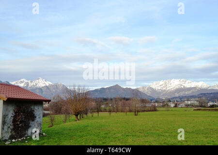 Vue panoramique à partir de Molteno de Grigna et Resegone mountain range couvert de neige en hiver, ciel bleu cloudscape house et Brianza champs verts. Banque D'Images