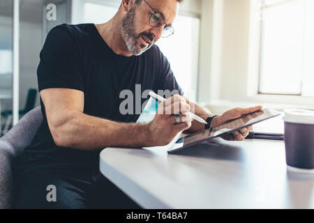 homme d'affaires travaillant sur la tablette numérique marquant peu de points d'importation avec un stylet. Entrepreneur masculin vérifiant les e-mails sur sa tablette. Banque D'Images