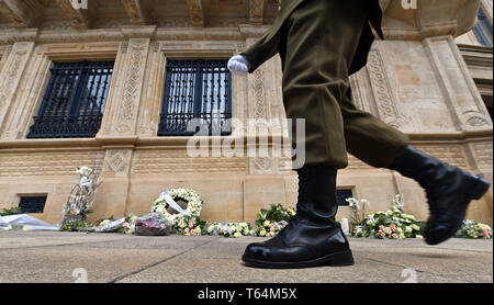 Luxembourg, Luxembourg. Apr 29, 2019. Un garde marche dernières portées et des couronnes de fleurs devant le Palais grand-ducal à Luxembourg. Le corps de l'ancien Grand-duc Jean a été aménagé dans le palais pendant cinq jours. Credit : Harald Tittel/dpa/Alamy Live News Banque D'Images