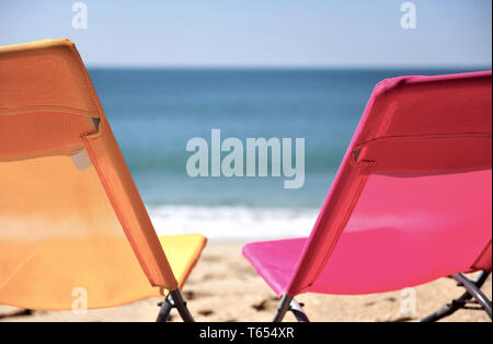 Deux chaises colorées sur plage de sable fin Banque D'Images