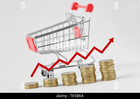 Pile de pièces de monnaie avec la flèche et panier à l'arrière-plan - Concept d'augmentation des achats Banque D'Images