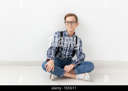 Adolescent, enfants et fashion concept - Cute child avec lunettes assis sur le marbre sur fond blanc Banque D'Images