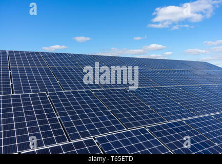 Des panneaux solaires sur un toit avec un ciel bleu et des nuages blancs de fond Banque D'Images