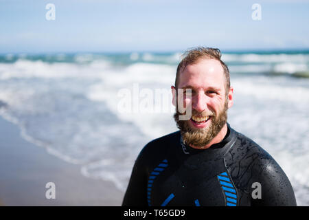 L'homme en combinaison de triathlon sur la plage Banque D'Images