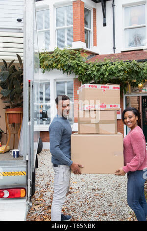 Portrait couple heureux déménagement, transportant des boîtes de carton dans l'entrée Banque D'Images