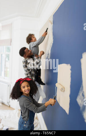 Portrait of cute girl painting wall avec père et frère Banque D'Images
