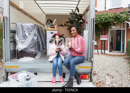 Heureux Portrait mère et fille de boire du thé à l'arrière du camion de déménagement, déménagement Banque D'Images