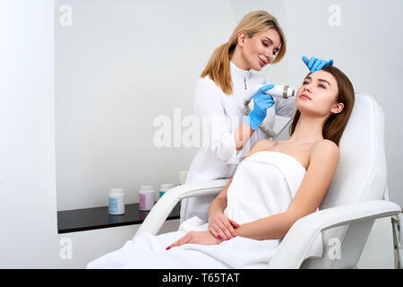 Jolie blonde doctor coiffeur rf-Procédure de levage pour femme fixant dans un salon de beauté. Cosmétologie matérielles. Patient recevant electric f Banque D'Images