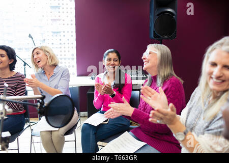 Choeur de femmes heureux avec partitions chant et applaudissement dans studio d'enregistrement musique Banque D'Images