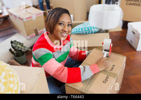 Portrait souriant, confiant woman packing moving boxes Banque D'Images